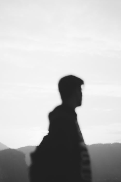 Silhouette of unrecognizable male tourist admiring mountains