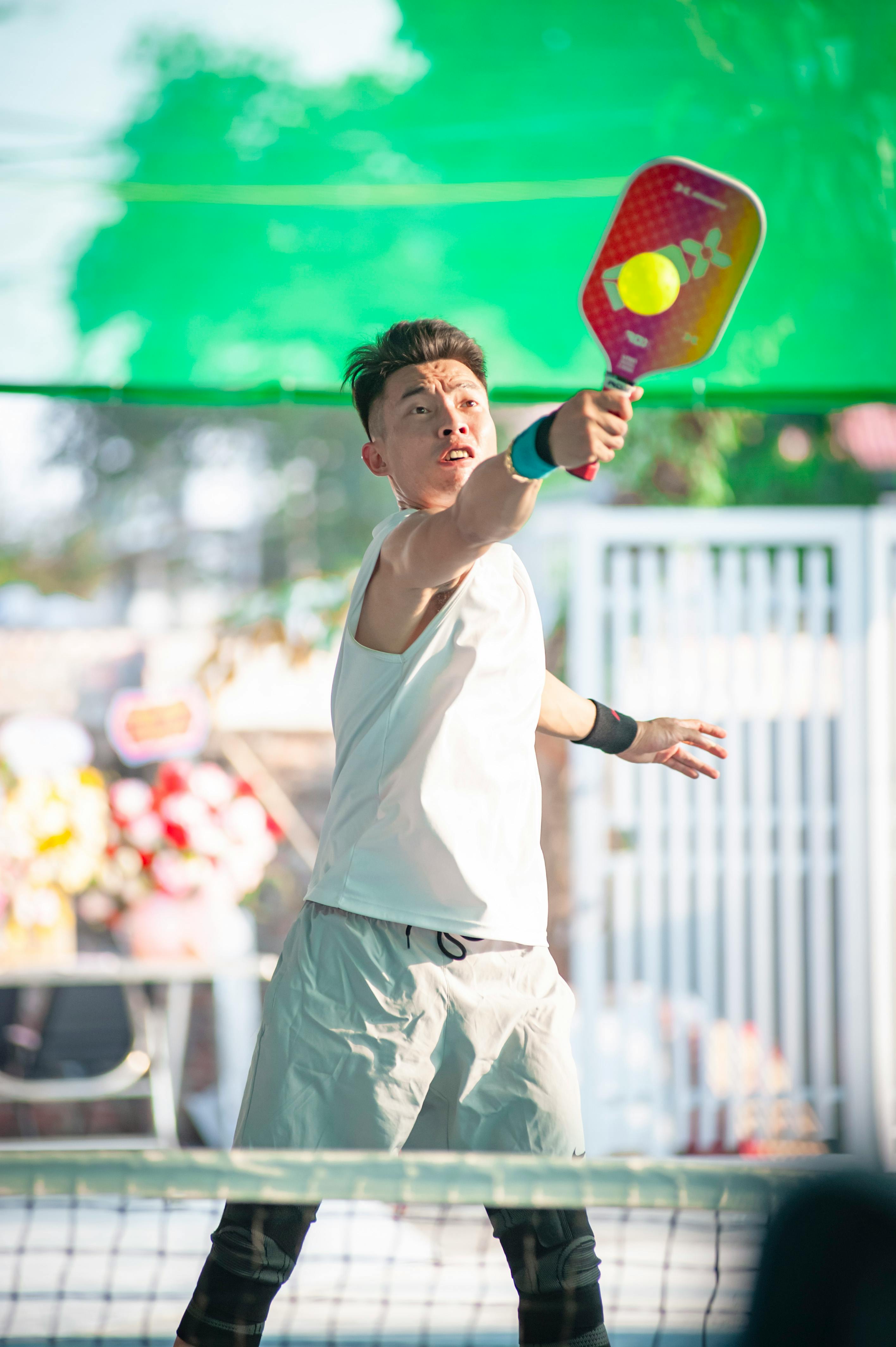 Focused young man playing pickleball outdoors