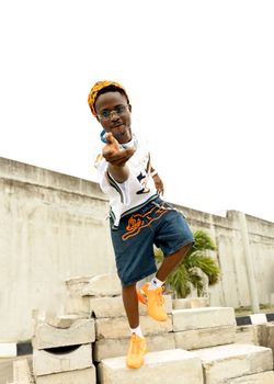 Energetic young man striking a street dance pose on concrete blocks outdoors.