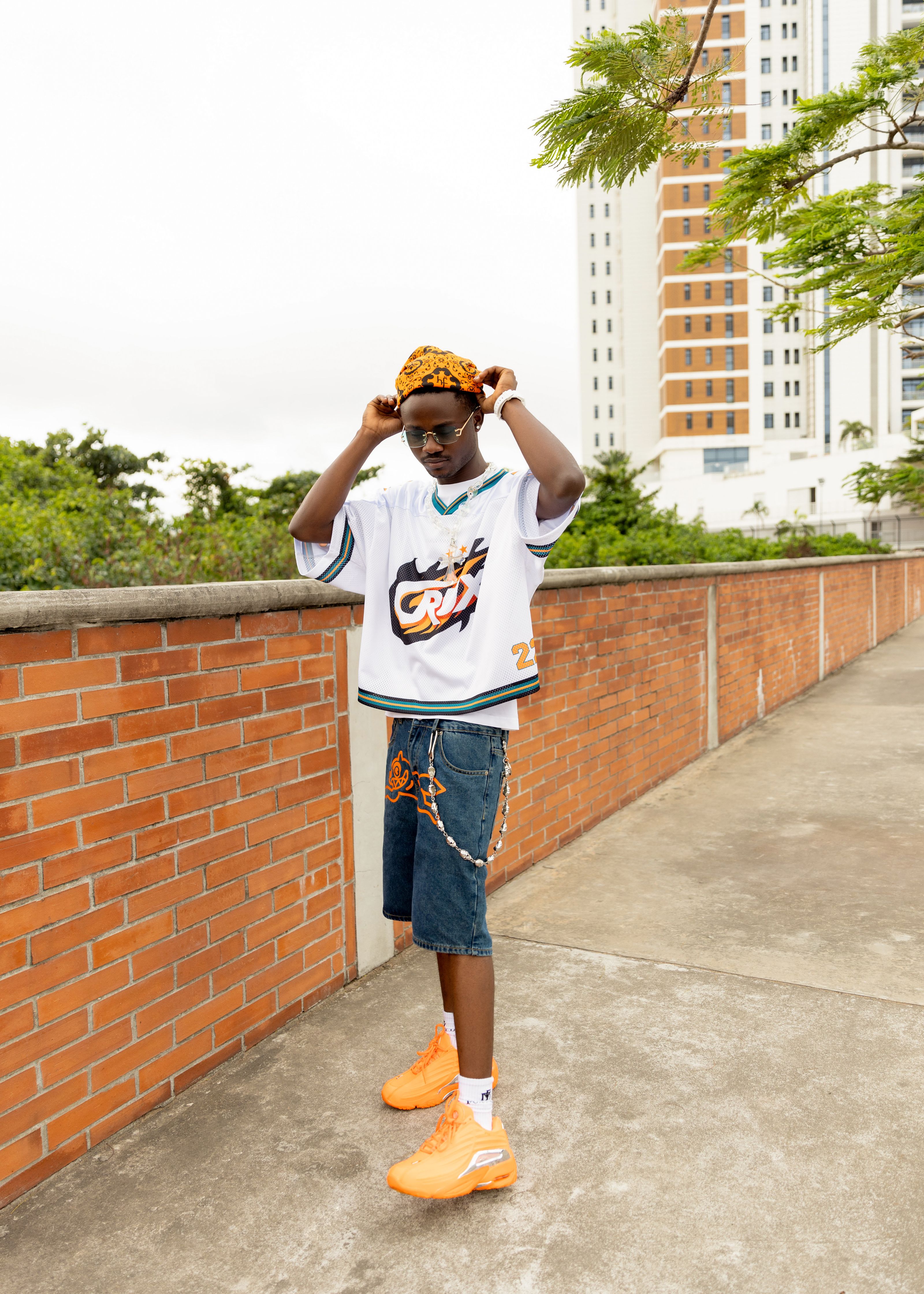 Um jovem da moda posa ao ar livre com um look urbano moderno, exibindo um estilo casual.