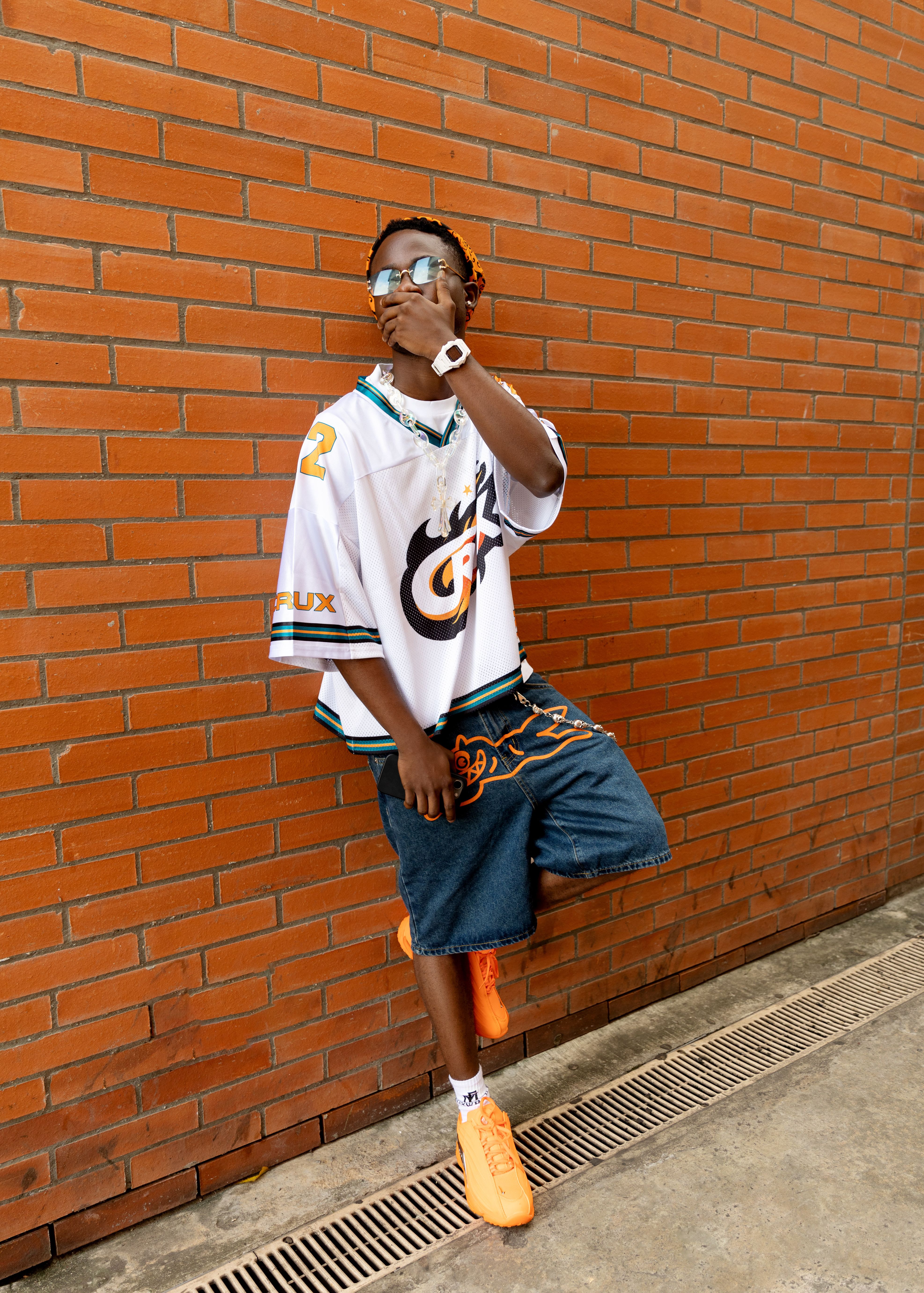 Stylish individual leaning against a brick wall, showcasing modern fashion.