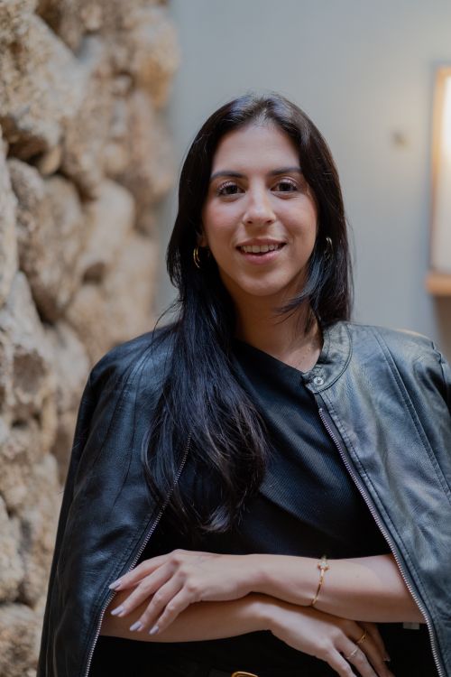 Free Confident young woman in leather jacket posing against stone wall indoors. Stock Photo