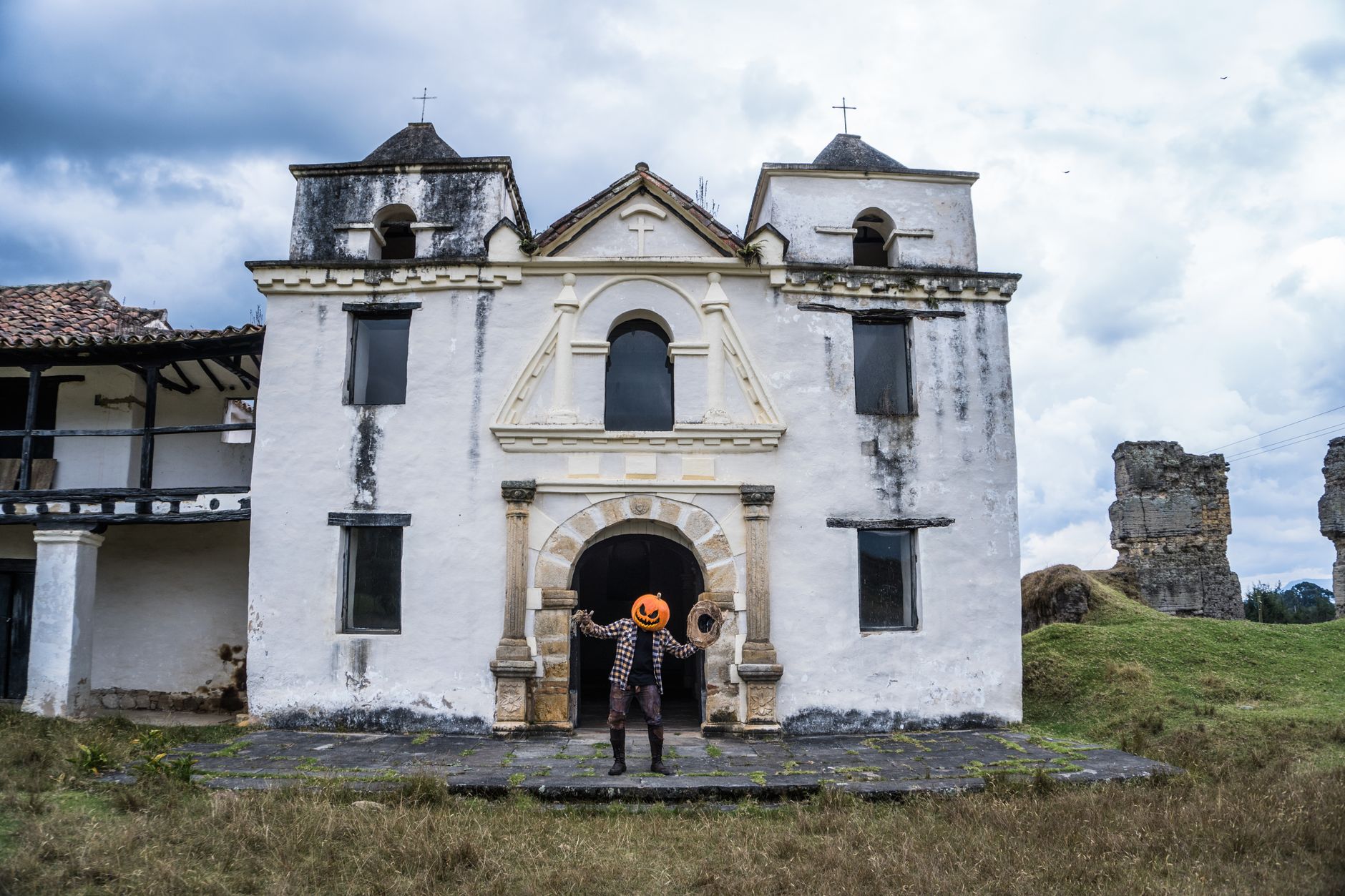 A person in Halloween costume with pumpkin head at old chapel in Guasca, Colombia.