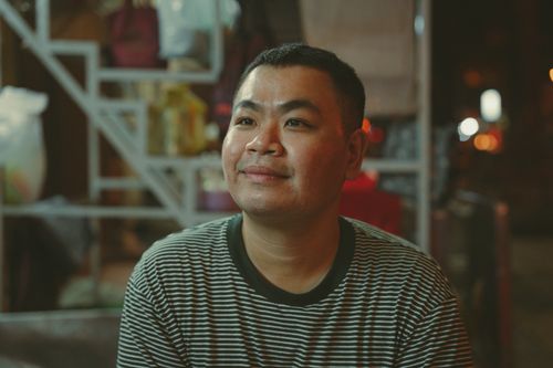 Free Portrait of an adult seated outdoors at a bustling night market in Ho Chi Minh City, Vietnam. Stock Photo