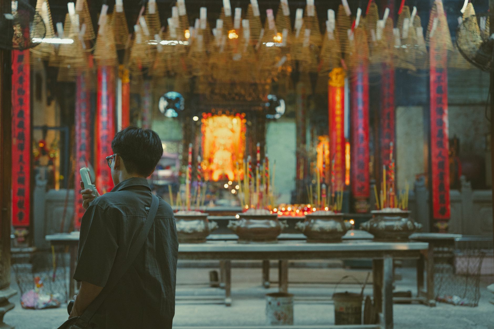 A man capturing the view inside a traditional Vietnamese temple filled with incense and vibrant decor.