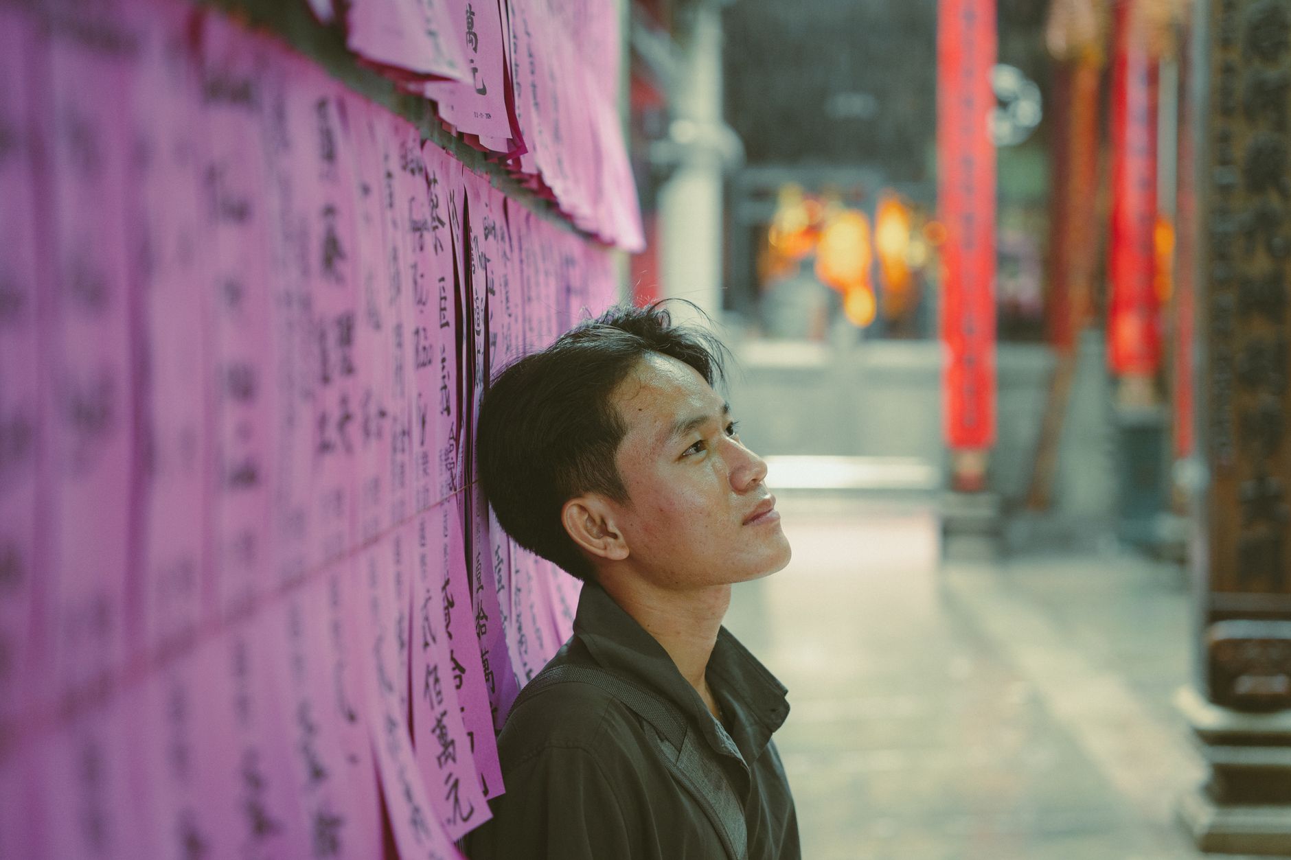 Young man reflects in a vibrant Ho Chi Minh City temple adorned with colorful banners.