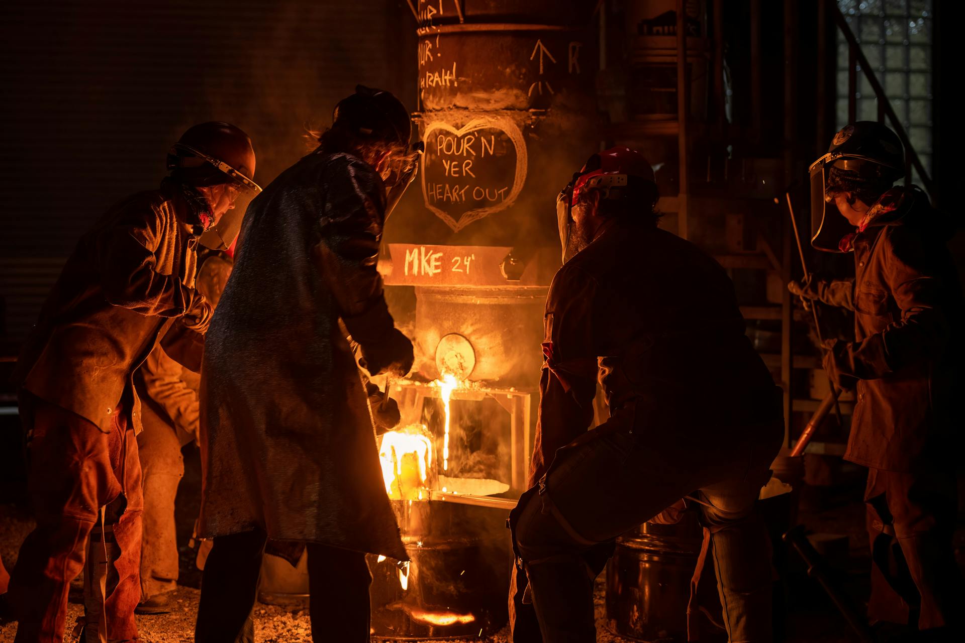 Metalworkers in Milwaukee pour molten metal from a furnace at night, creating an industrial scene.