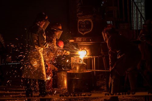 Free Dynamic shot of foundry workers pouring molten metal at night in Milwaukee industrial setting. Stock Photo