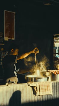 A street vendor skillfully pours hot chai tea in an outdoor market.