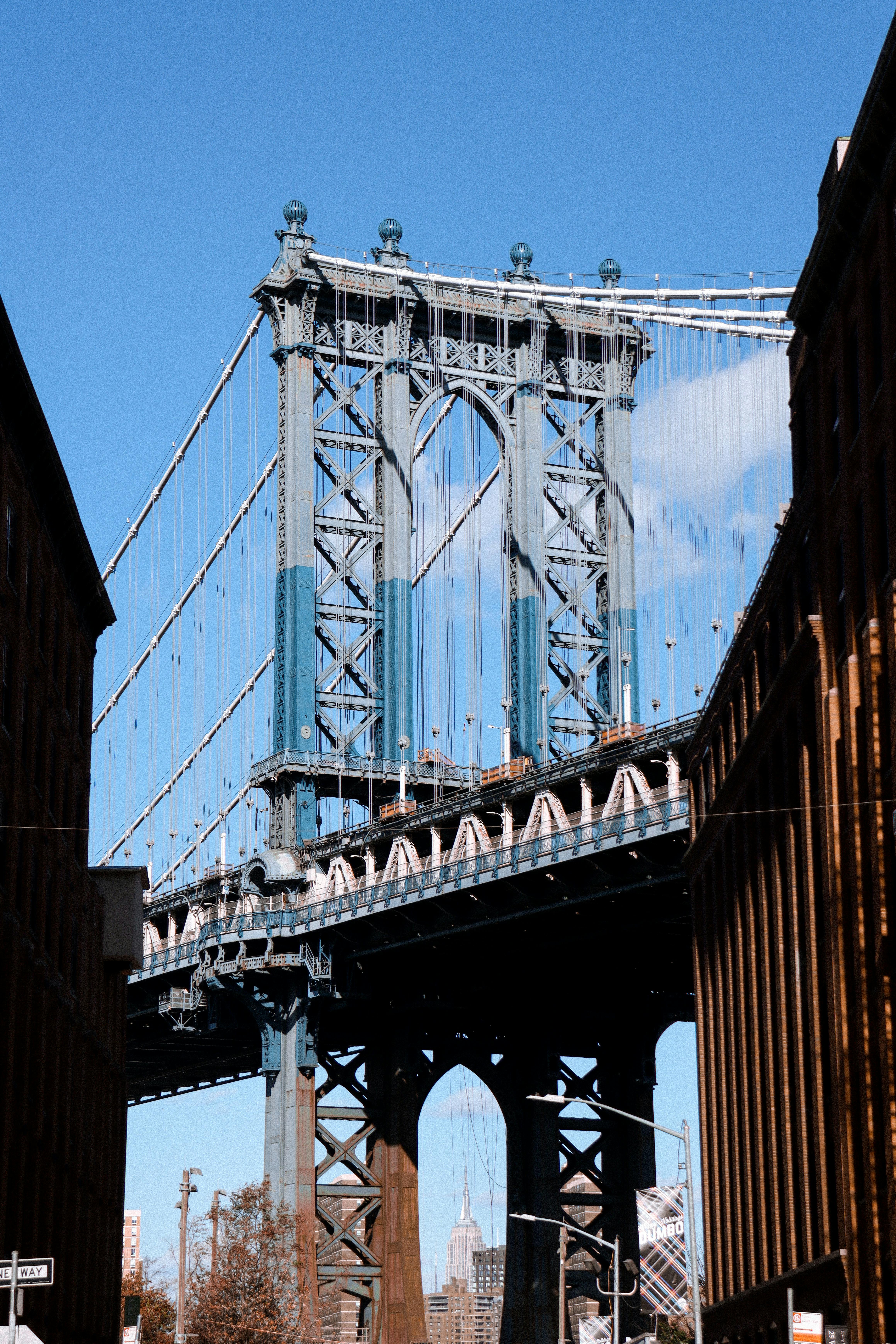 Classic view of the Manhattan Bridge framed by city buildings in New York. Bright clear sky.