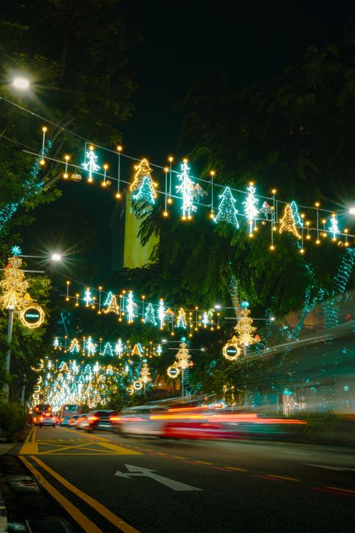 Free Vibrant Christmas street scene showcasing dazzling light decorations and colorful car trails at night. Stock Photo