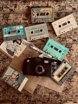 A collection of vintage cassette tapes and a classic camera on a patterned surface, evoking nostalgia.