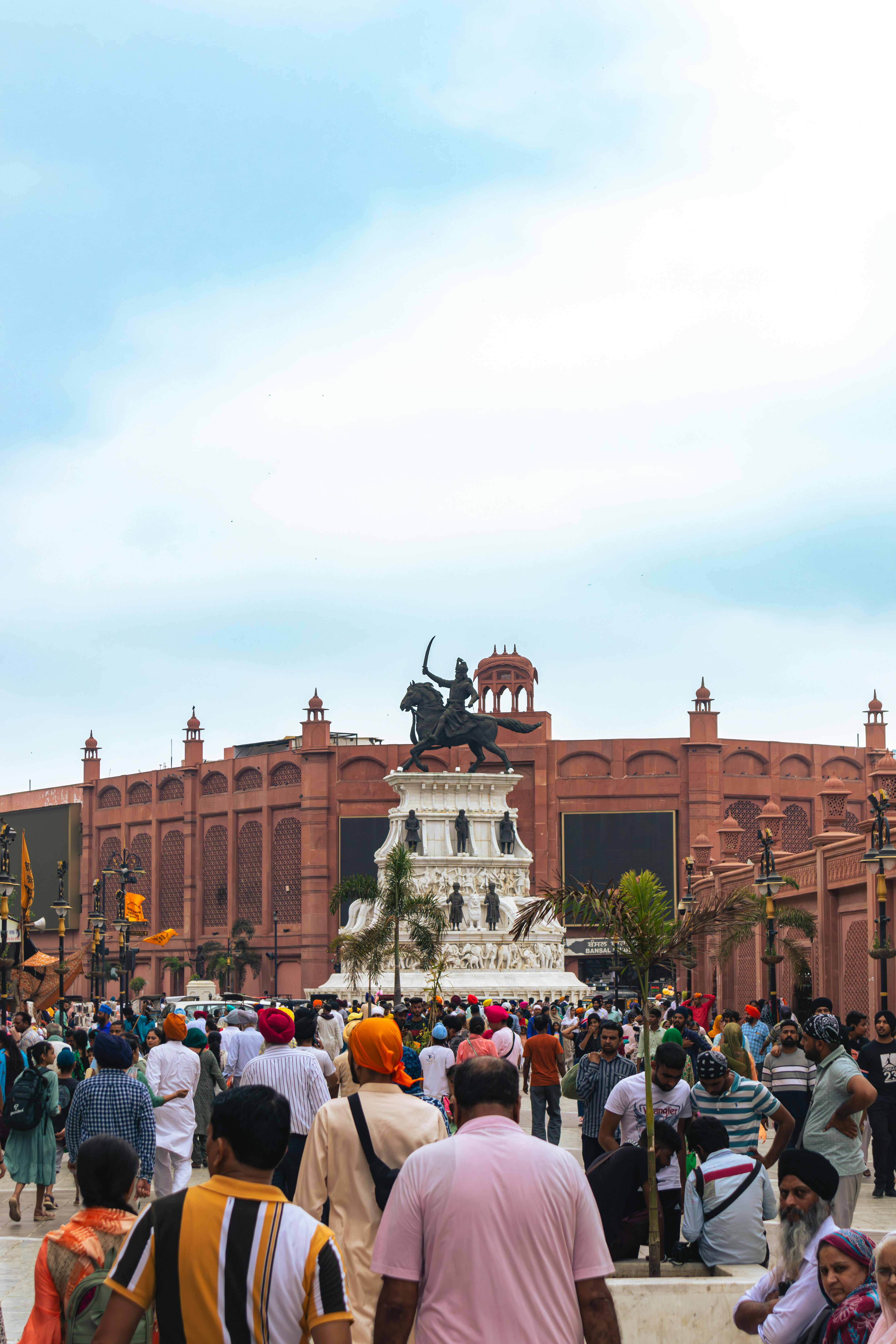 Bustling crowd around Maharaja Ranjit Singh's statue in Amritsar, showcasing Sikh culture.