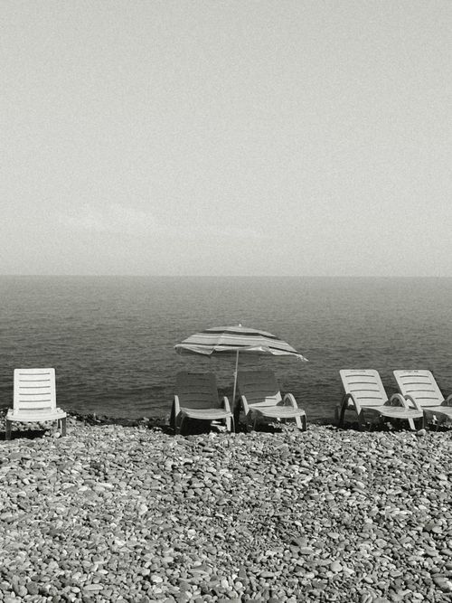 Free Monochrome view of a pebble beach with sunbeds and umbrella on the Black Sea coast in Batumi, Georgia. Stock Photo