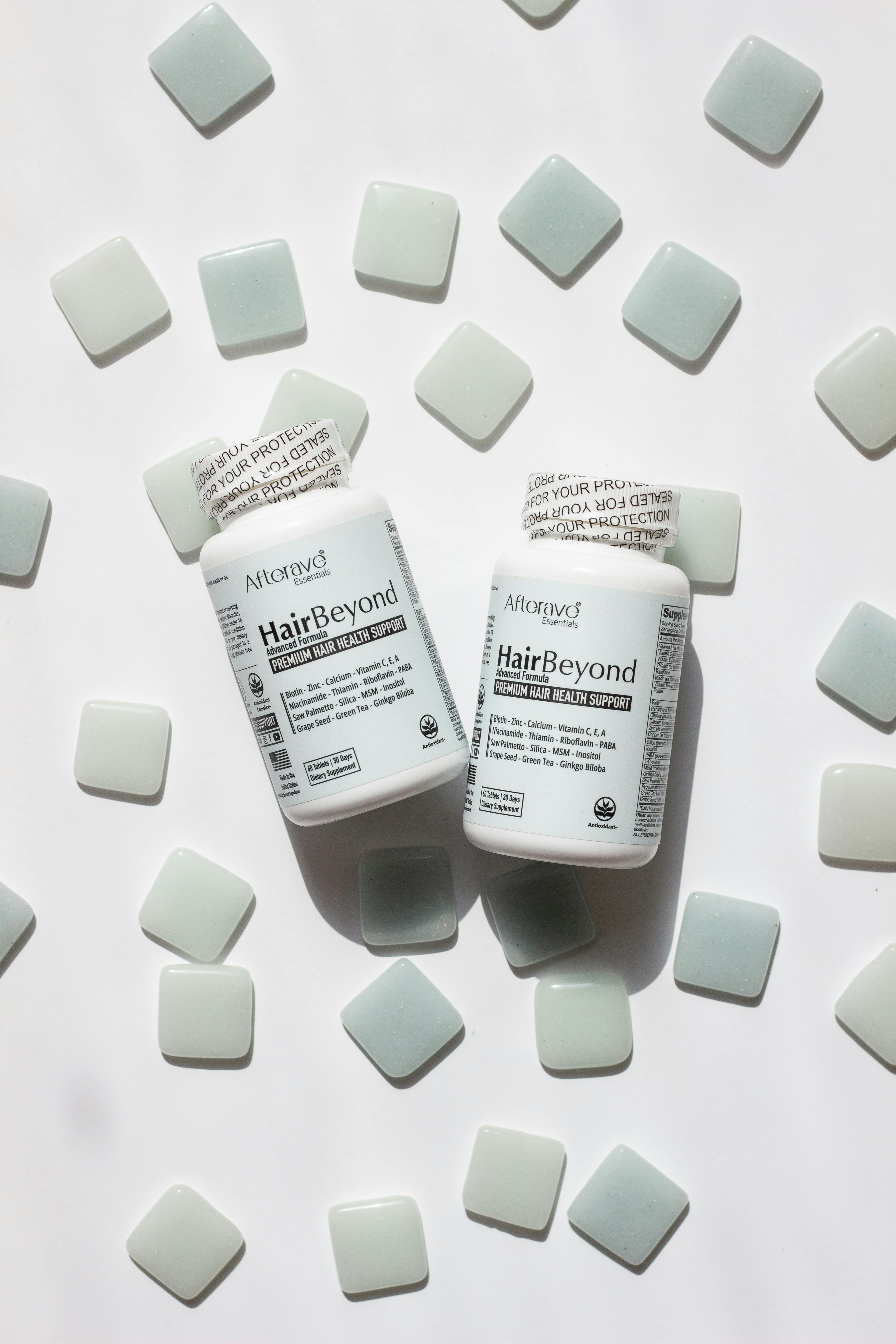 Close-up of HairBeyond vitamin bottles surrounded by tiles, ideal for hair and nail health.