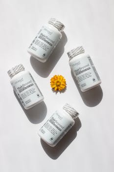 Stylish flat lay featuring HairBeyond vitamins and a marigold flower on a neutral background.