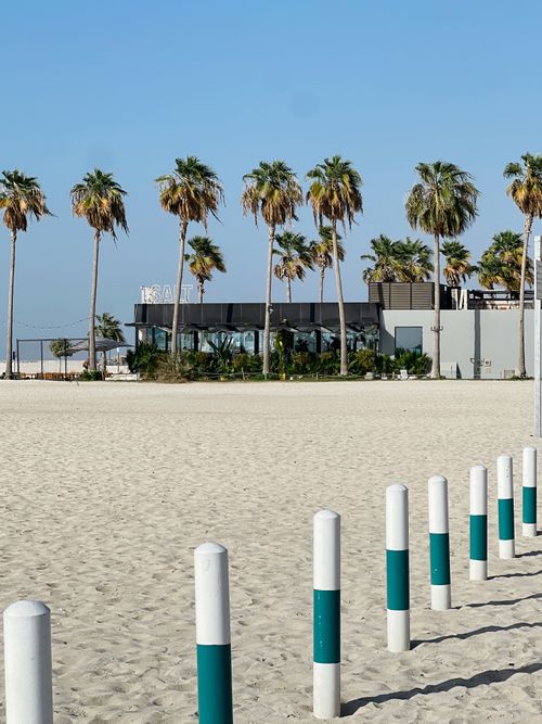 Free A scenic view of palm trees and a beachside restaurant under a clear blue sky. Stock Photo