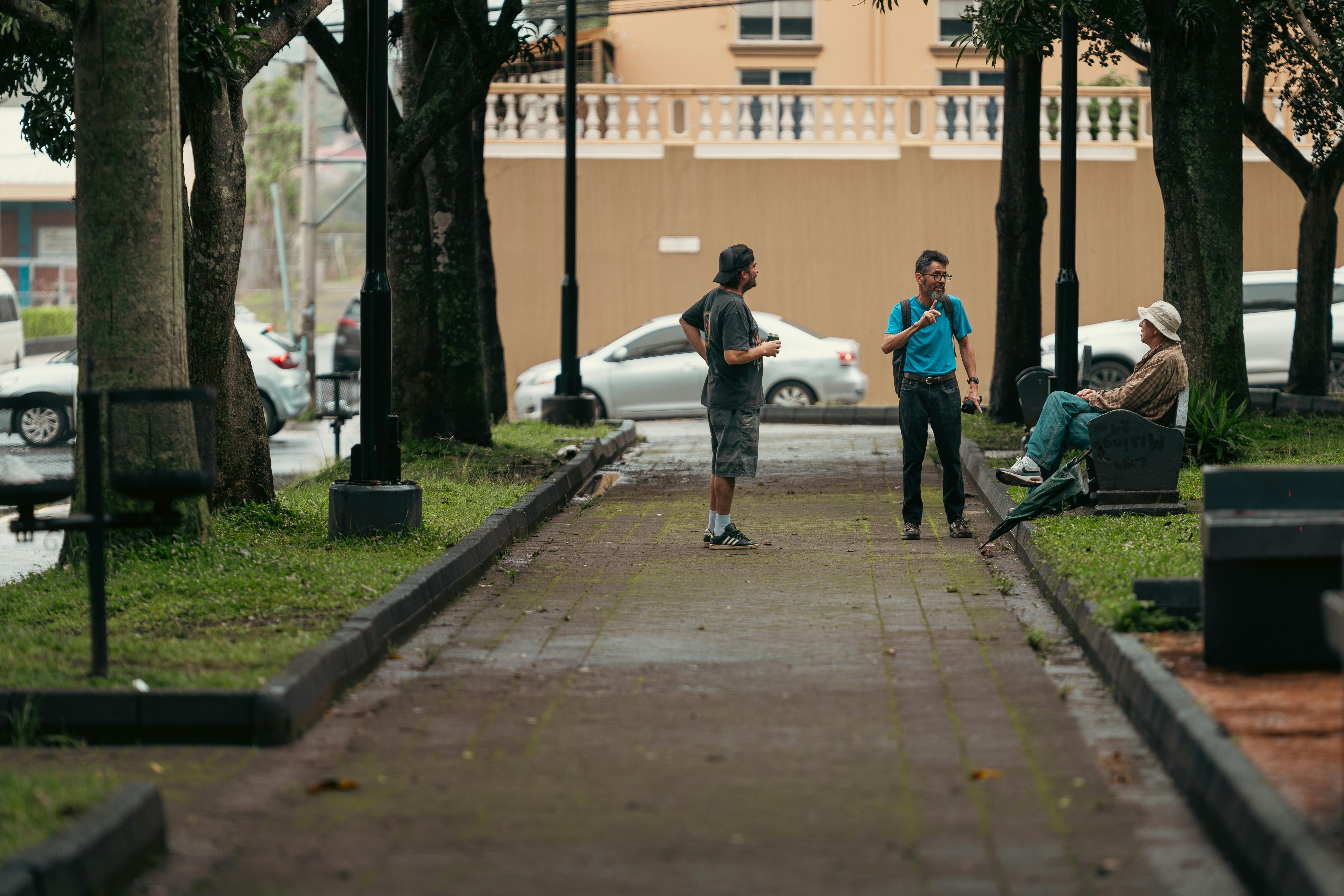 Gratis Et ærligt gadebillede af tre mænd, der samtaler i en park i Alajuela, Costa Rica. Lagerfoto