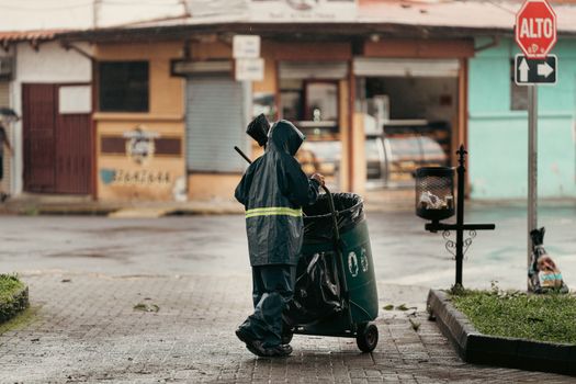 A street cleaner in a raincoat works on a wet street in Alajuela, Costa Rica.