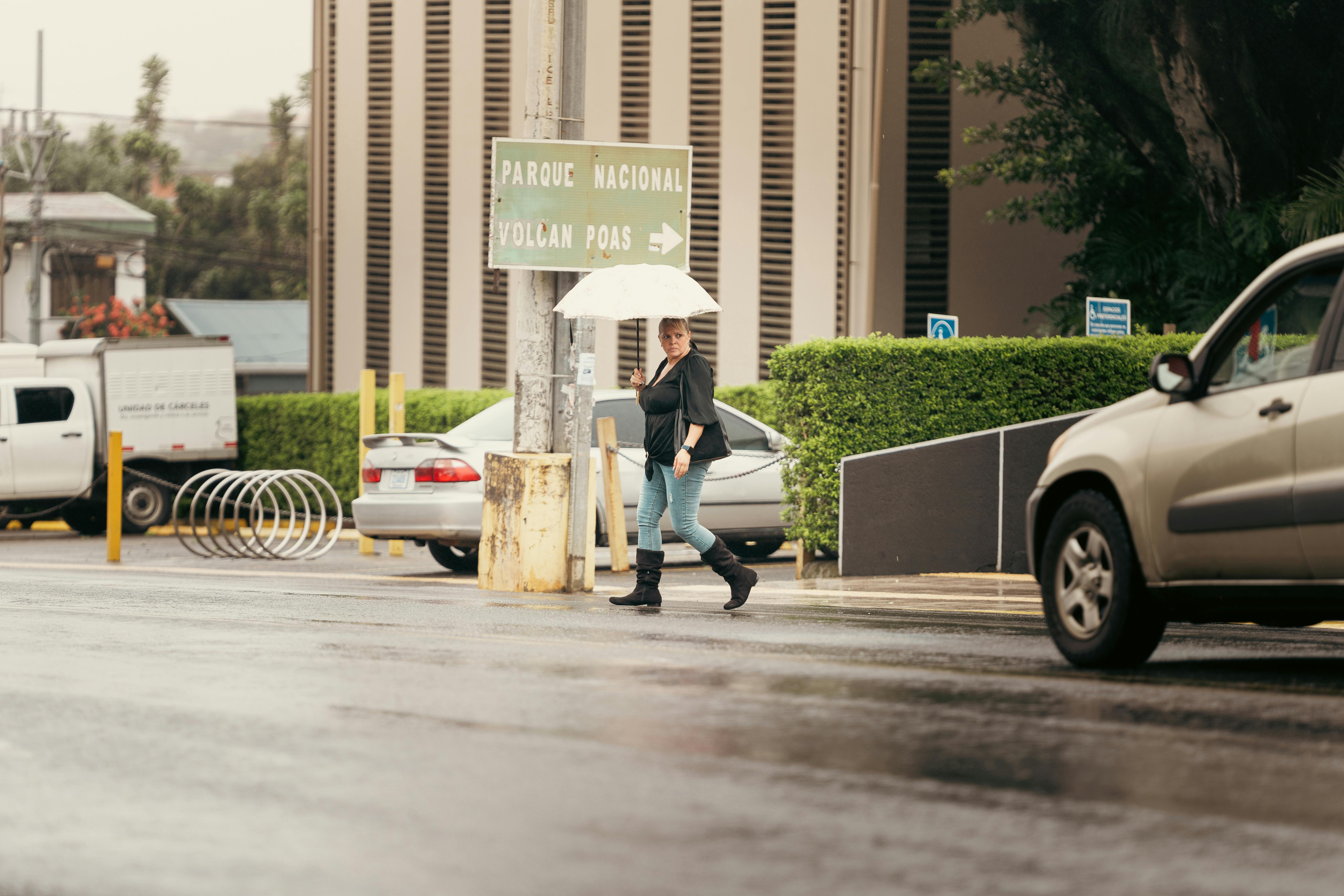 A woman crossing a rainy street in Alajuela, Costa Rica with an umbrella.