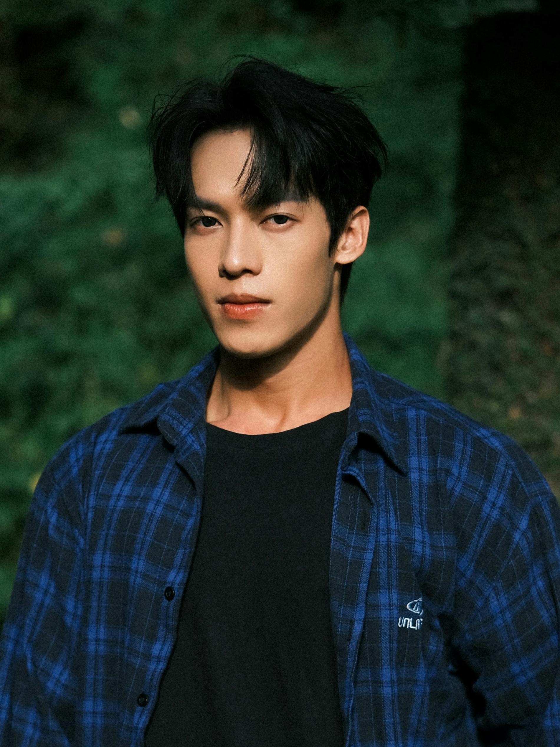 Portrait of an adult male in a blue plaid shirt outdoors with a neutral expression.