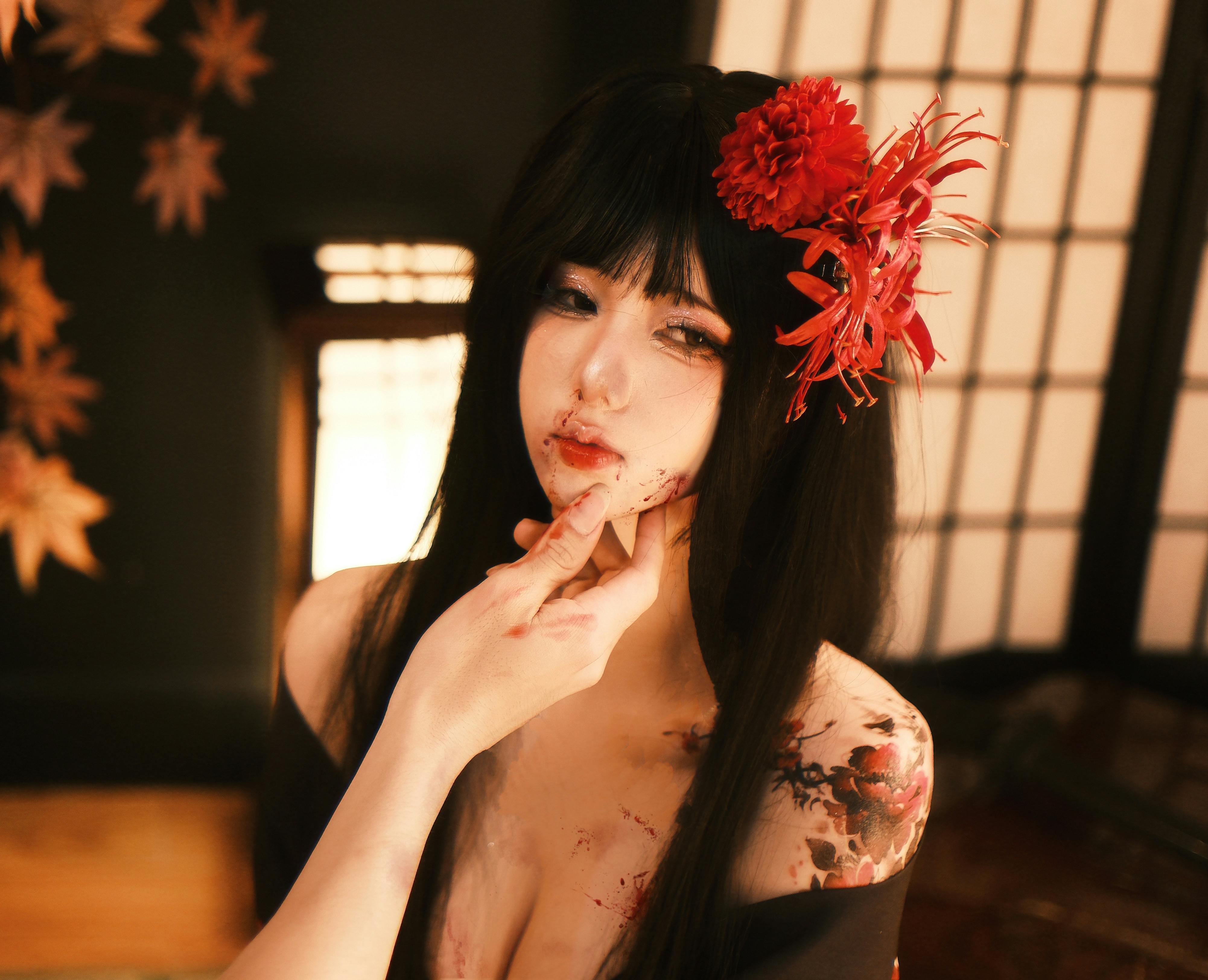 Artistic indoor portrait of a woman in cosplay with red flower accessory and autumn theme. Dramatic lighting.