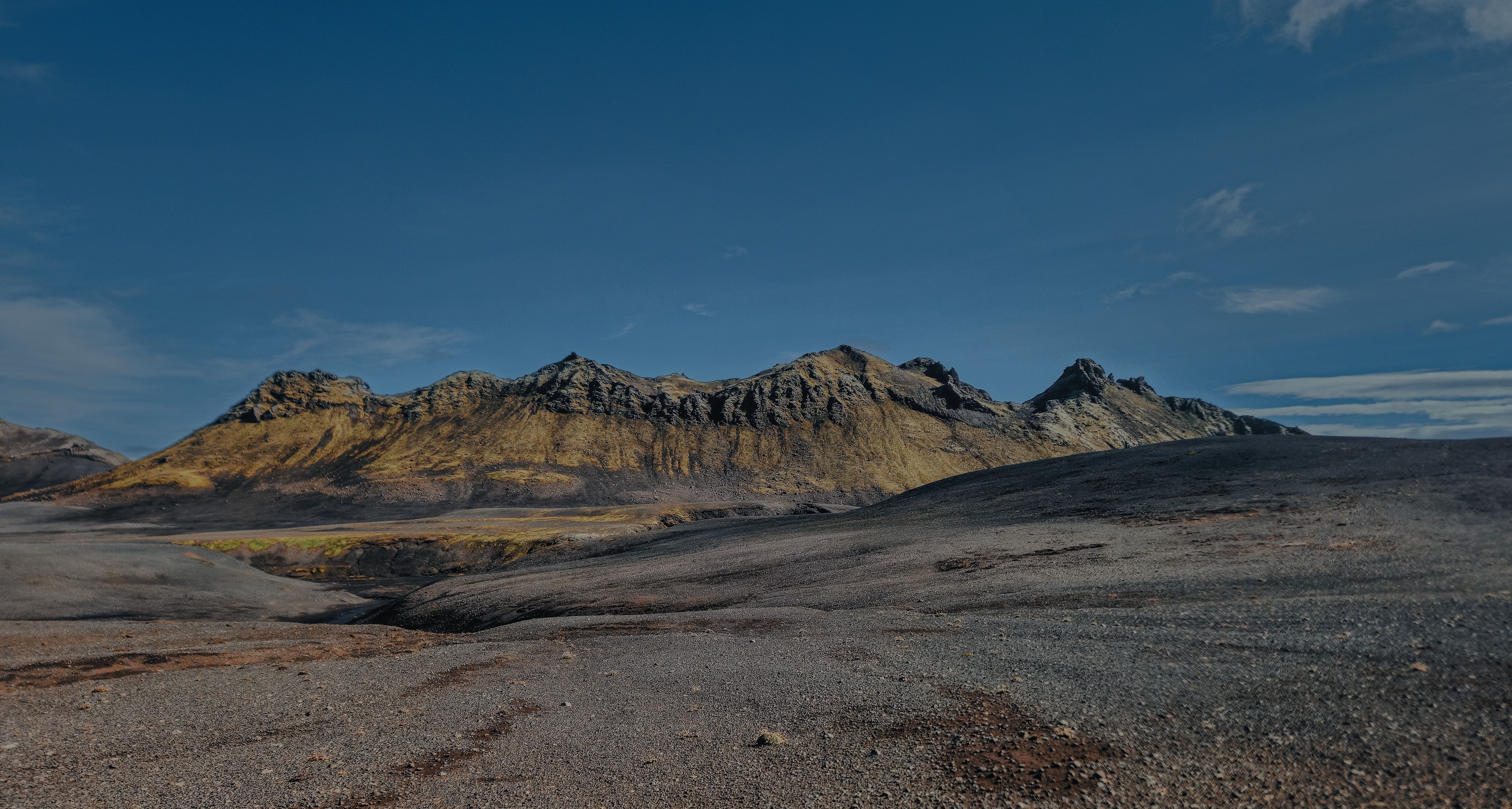 Expansive volcanic landscape in Þingeyjarsveit, Iceland, under clear blue sky.
