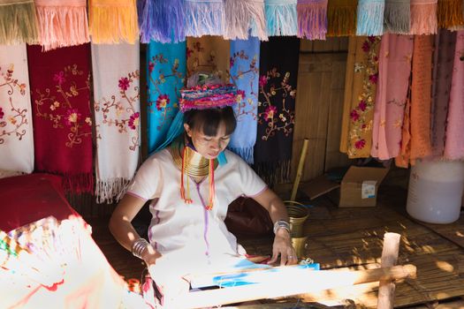 Long Neck Karen woman weaving traditional textiles in Chiang Mai, Thailand.