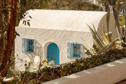 Free A picturesque traditional house with blue accents in Carthage, Tunisia, surrounded by greenery and cacti. Stock Photo