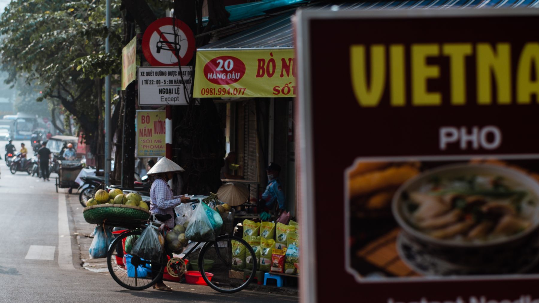 Uma cena vibrante de um vendedor de rua vietnamita com uma bicicleta carregada de produtos em Hanói.