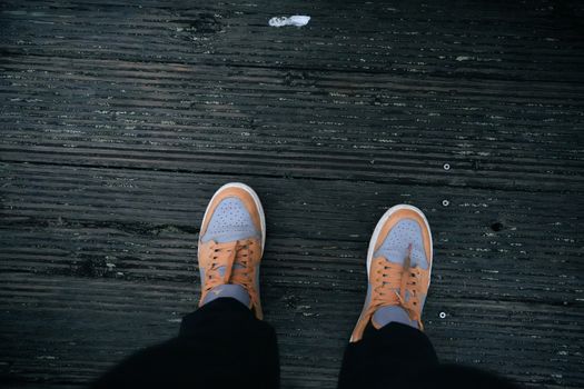 Top-down view of orange sneakers on a wooden deck, offering a casual lifestyle vibe.
