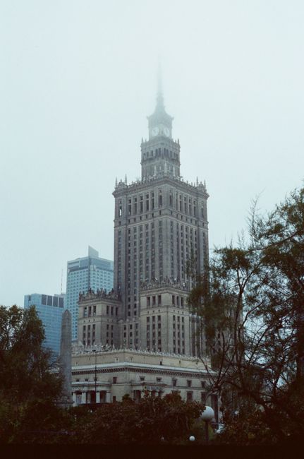The iconic Palace of Culture and Science in Warsaw enveloped in fog on a misty day.
