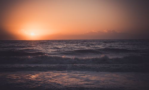 Free Serene ocean scene at sunset with gentle waves and warm sky. Stock Photo