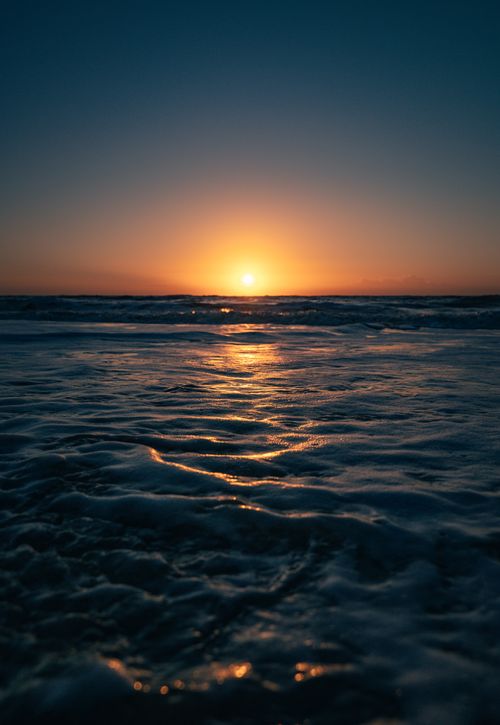 Free Capture of a stunning sunset over the ocean with vibrant colors and serene waves. Stock Photo