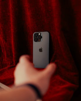 Stylish smartphone positioned on a red velvet fabric, hand reaching out.