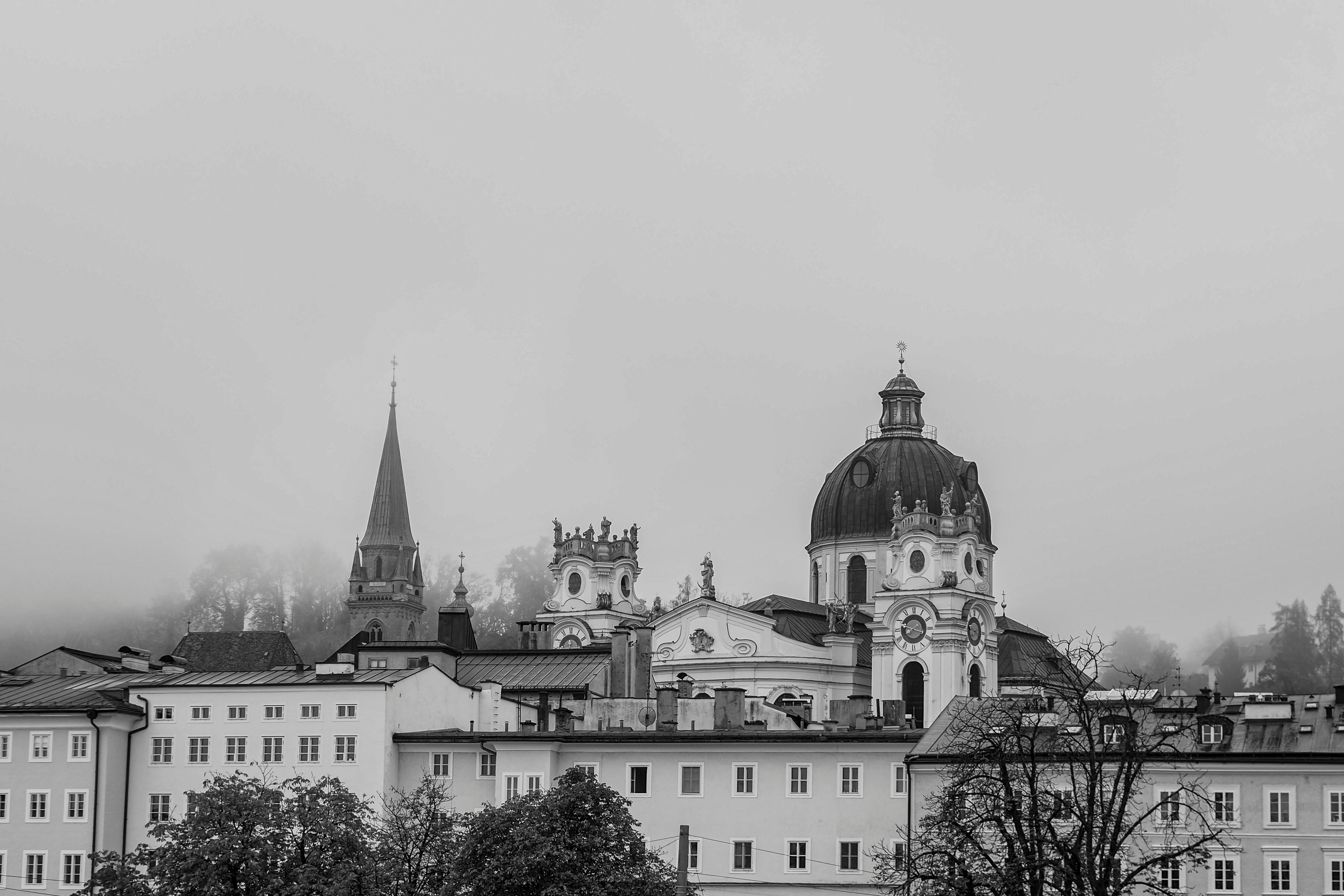 Black and white view of Salzburg's historic architecture shrouded in mist.