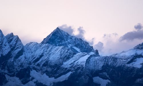 Free Majestic snow-covered peaks of the Italian Alps under a pastel sky at sunset. Stock Photo