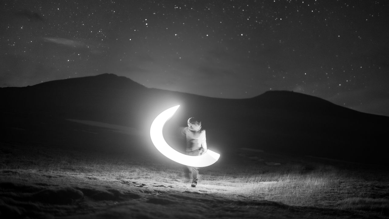 a solitary person exploring a mountainous starry landscape at night