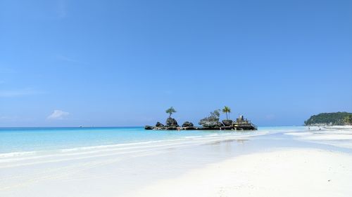 Free A breathtaking view of a serene tropical beach with crystal-clear azure waters and fine white sand. Stock Photo