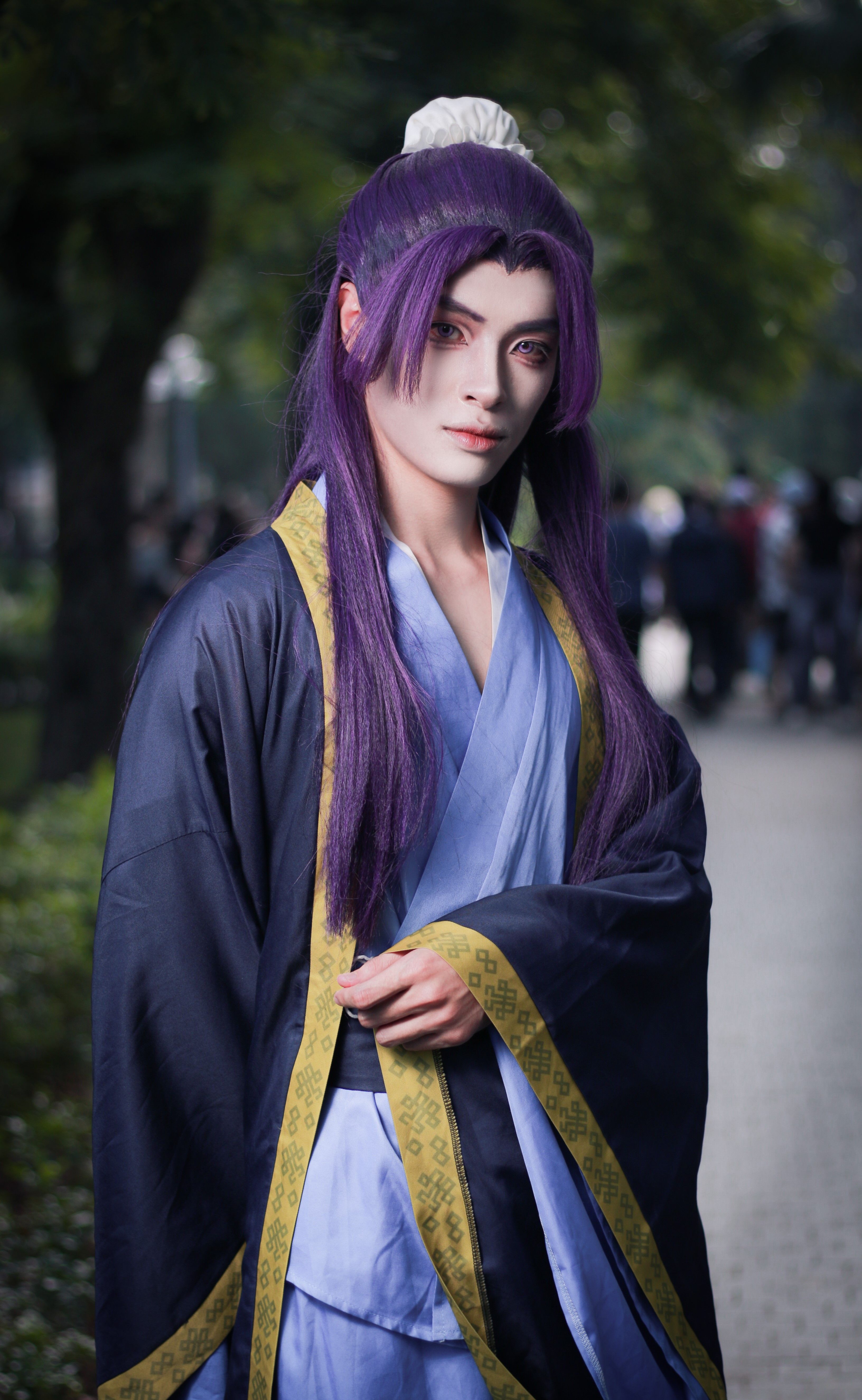 Anime cosplay with purple hair and traditional robe outdoors.