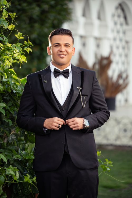 Free A confident man in a black tuxedo outside, exuding elegance and style. Stock Photo