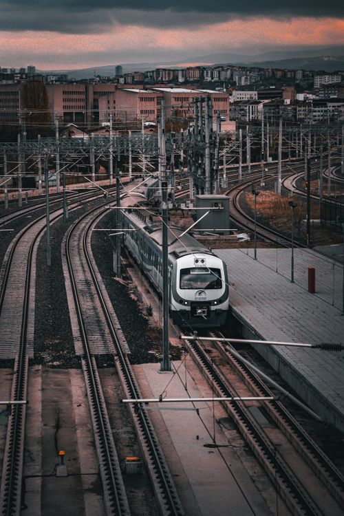 Free A modern railway train on tracks in a city at sunset, offering dynamic urban transit imagery. Stock Photo