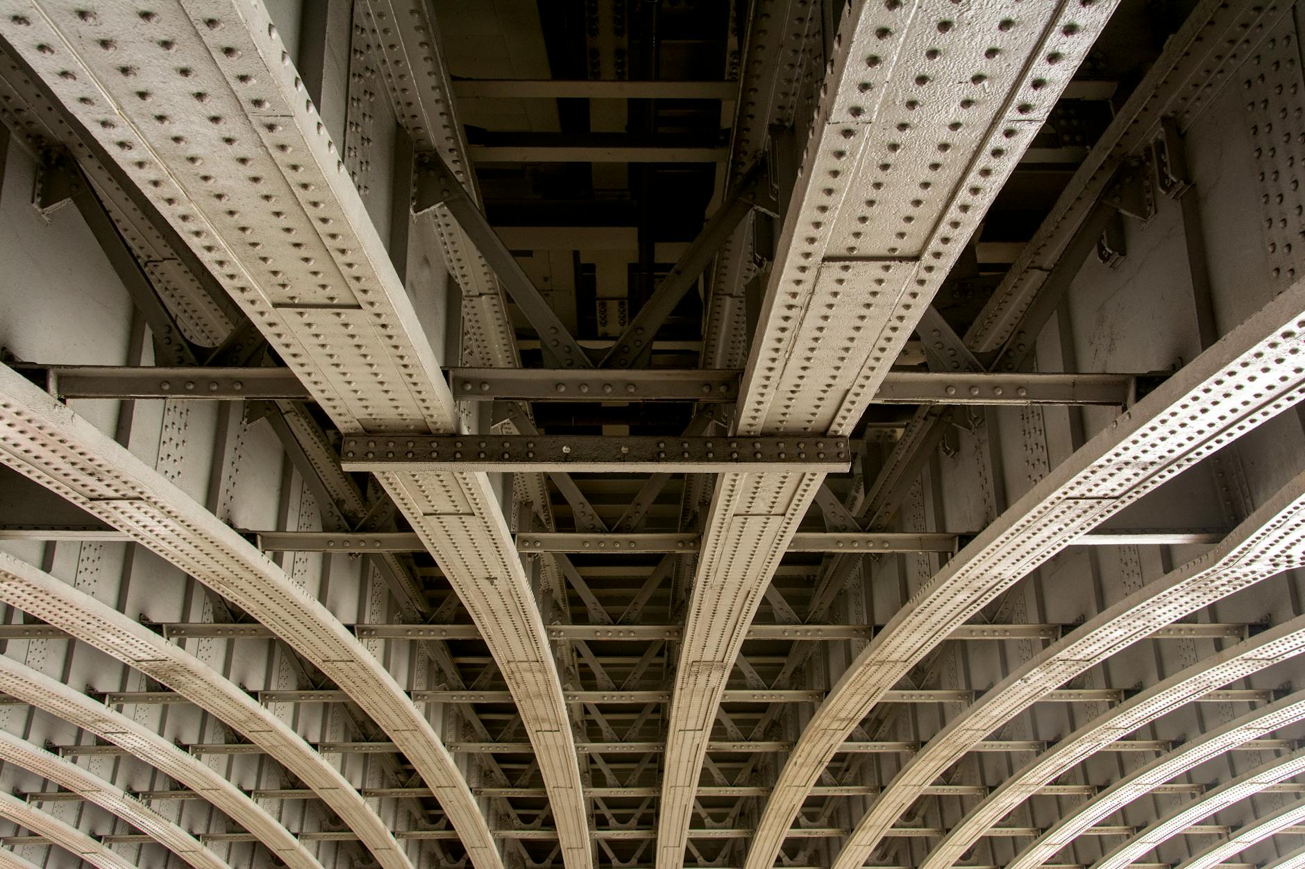 Detailed view of the steel framework underside of a bridge showcasing riveted construction.