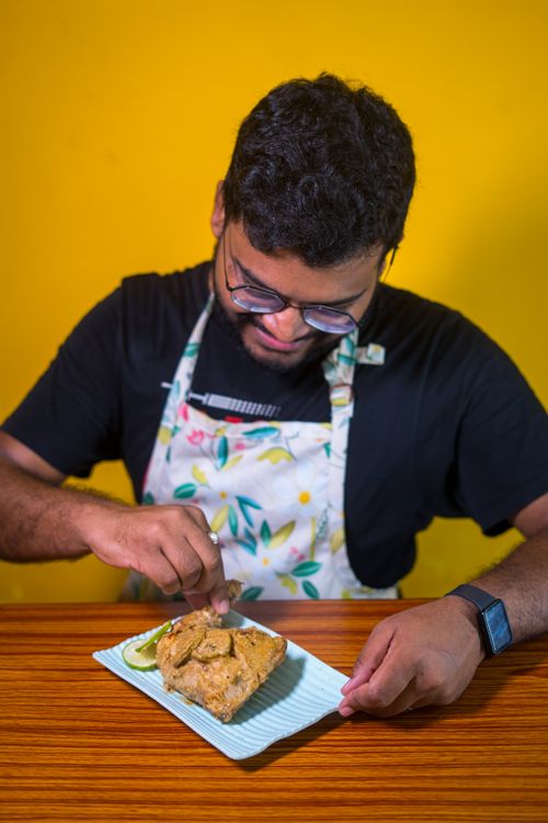 Free A person cooking a savory dish with garnish on a plate, wearing an apron. Stock Photo