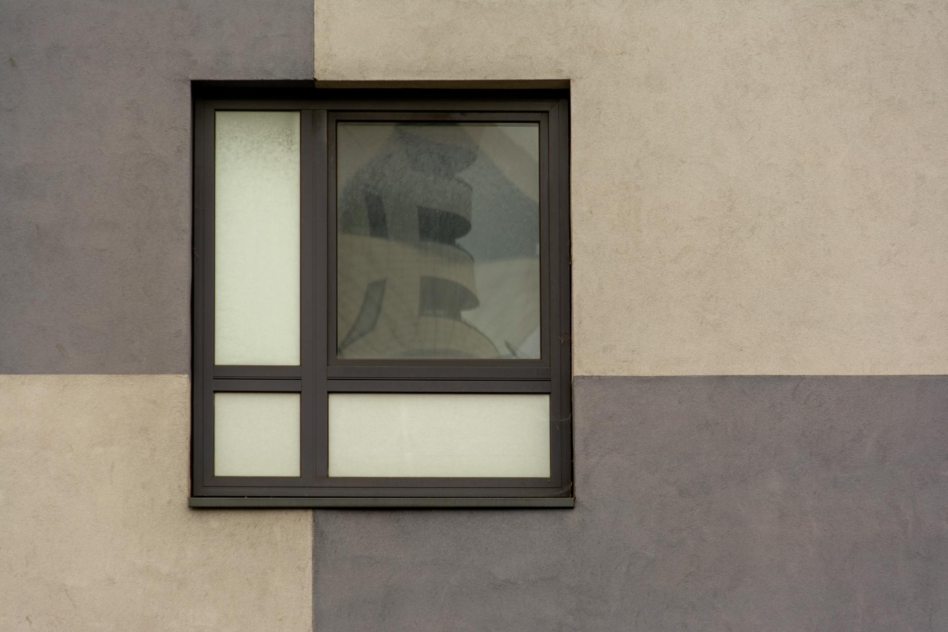 A minimalist architectural facade featuring a window with contrasting colors.