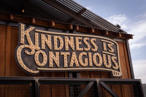 Free Rustic sign with 'Kindness is Contagious' message on a wooden barn background. Stock Photo