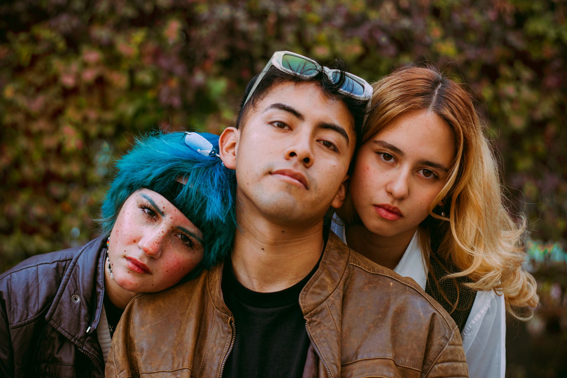 Three young adults with unique fashion posing confidently outside.