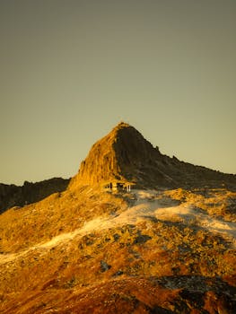 Capture the serene beauty of a sunlit alpine peak in Andermatt, Switzerland, perfect for adventure seekers.