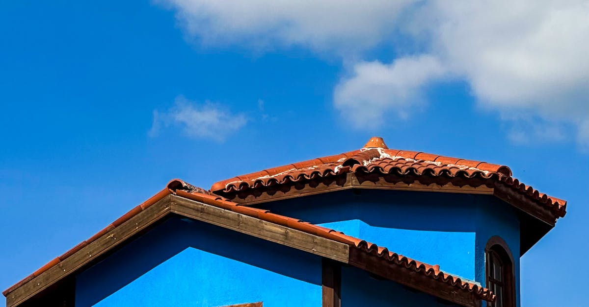 Vibrant Blue House with Rustic Red Roof Under Clear Sky · Free Stock Photo