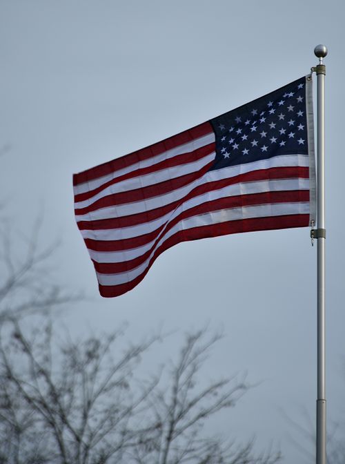 Free A vividly waving American flag against a clear blue sky symbolizing patriotism. Stock Photo